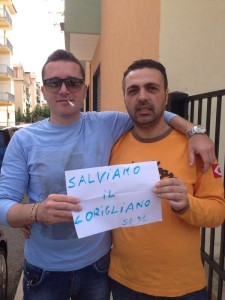 Due tifosi del Corigliano calcio espongono un foglio con la scritta "Salviamo il Corigliano"